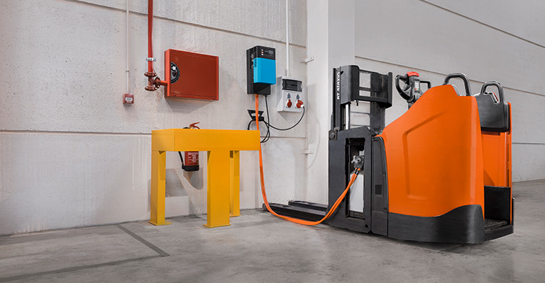 Transpalette électrique Toyota connecté à une station de charge dans un environnement industriel